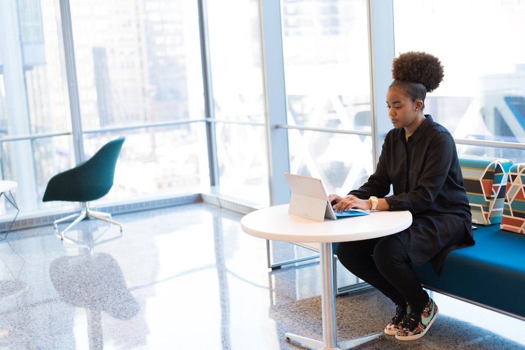 woman sits on sofa while using tablet computer in office workspace
