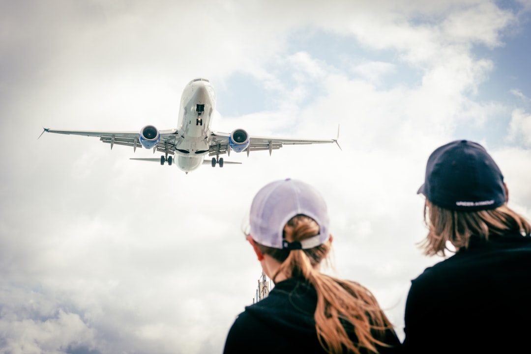 空港で飛行機を見上げる旅行者