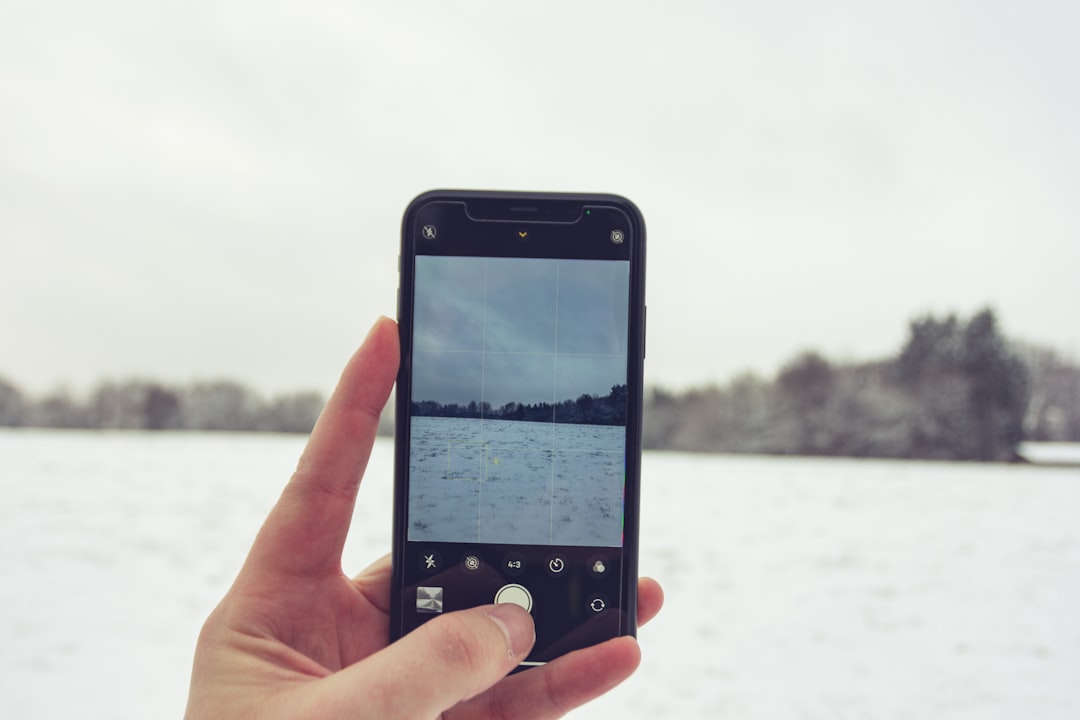 person holding iphone taking photo of body of water during daytime